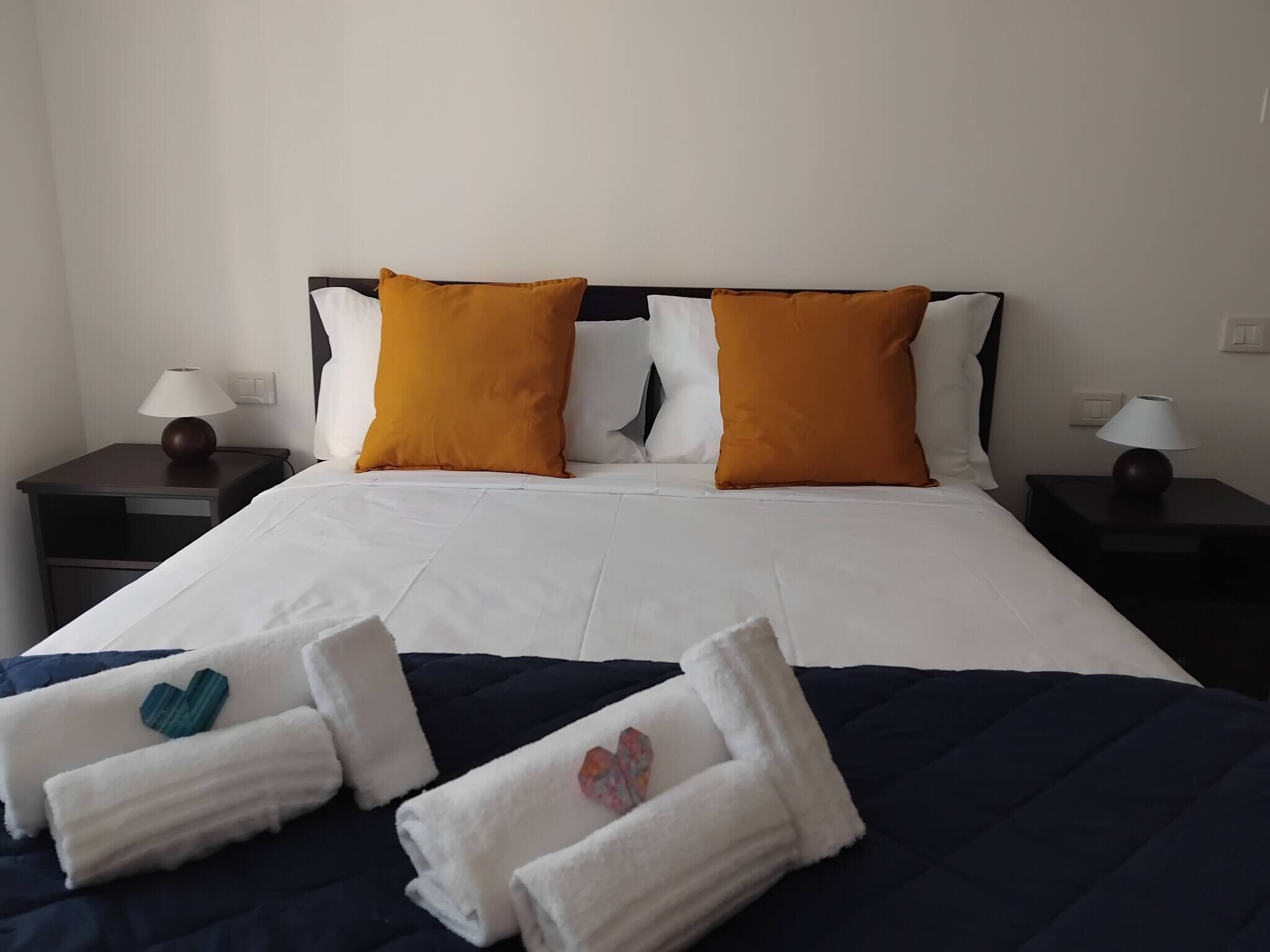A hotel room with a bed, two nightstands, and a set of towels.