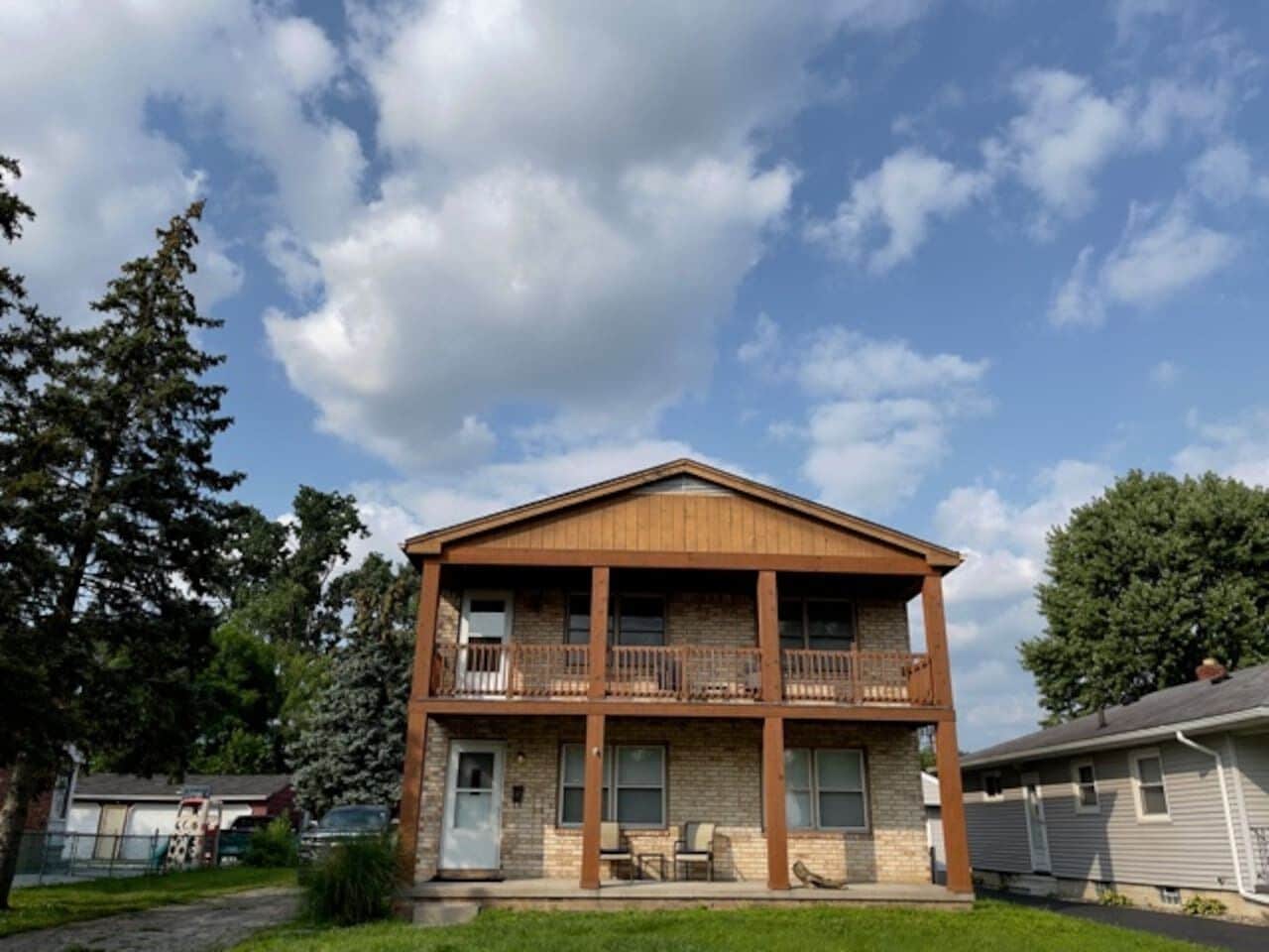 A two-story building with a balcony on the second floor, a front porch, and a brick facade.