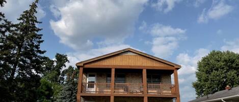 A two-story building with a balcony on the second floor, a front porch, and a brick facade.