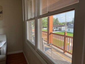 Ein Zimmer mit großem Fenster und Blick auf eine Terrasse mit Holzgeländer.