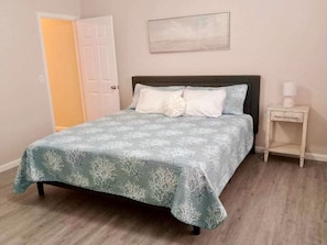 A bedroom with a bed, a nightstand, and a door. - Newly Renovated 3BR, 1.5 Bath w/ Enclosed Porch! (Rossford)