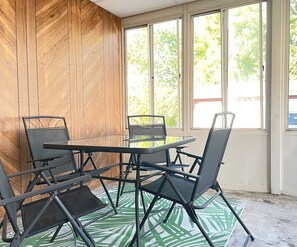 A room with a round table and four chairs, wooden walls, and large windows. - Long Stays Welcome! 3BR/1.5 bath (Rossford)