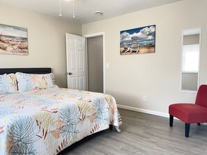 A bedroom with a bed, a red chair, and two paintings on the wall. - Long Stays Welcome! 3BR/1.5 bath (Rossford)