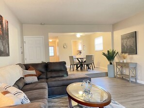 A living room with a sofa, coffee table, and dining area. - Long Stays Welcome! 3BR/1.5 bath (Rossford)