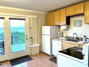 A kitchen with a refrigerator, dishwasher, and a view of the sea through a door. - “Bayview Shores" Stylish Lakefront Ground Level! (Toledo)