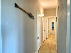 A hallway with white walls, wooden flooring, and a wall-mounted broom. - “Bayview Shores" Stylish Lakefront Ground Level! (Toledo)