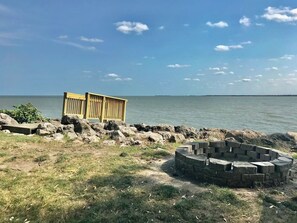 Una zona sul lungomare con una struttura in legno e un braciere in pietra.