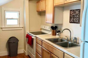 A kitchen with a stove, sink, and cabinets, and a 'Welcome to our Lake House' sign.