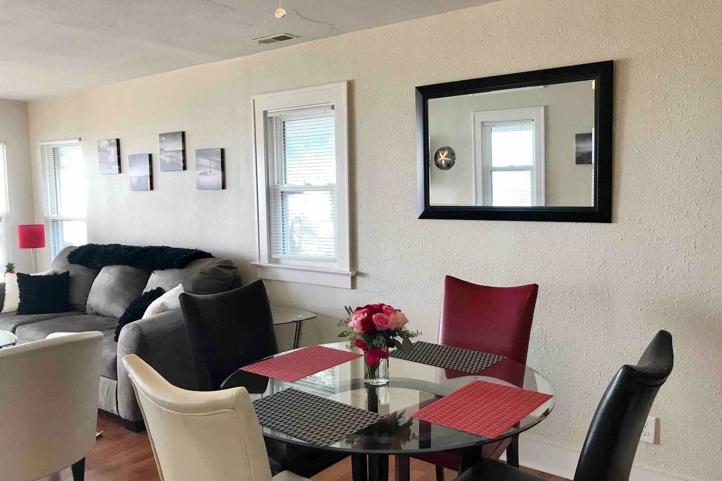 Ein Wohnzimmer mit einer Couch, einem Esstisch mit Stühlen, einem Couchtisch und einer Wanduhr.