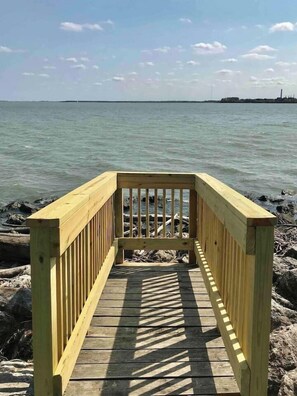 Une terrasse en bois qui mène à un plan d’eau, avec un ciel dégagé.