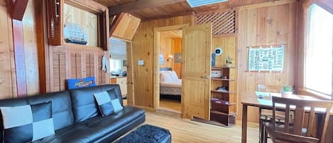 A cozy cabin interior with a sofa, a dining table, and a kitchenette area.