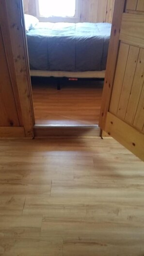Un plancher en bois mène à un lit doté d’un matelas bleu.
