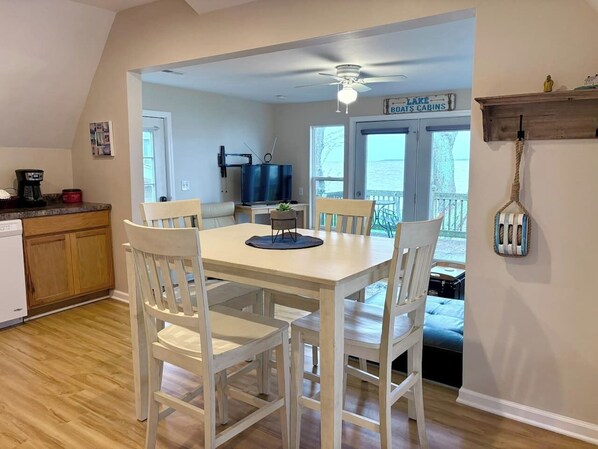 A dining area with a table and chairs, a ceiling fan, and a view of a boat cabin through a door.