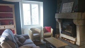Een woonkamer met een bank, fauteuil en een open haard.