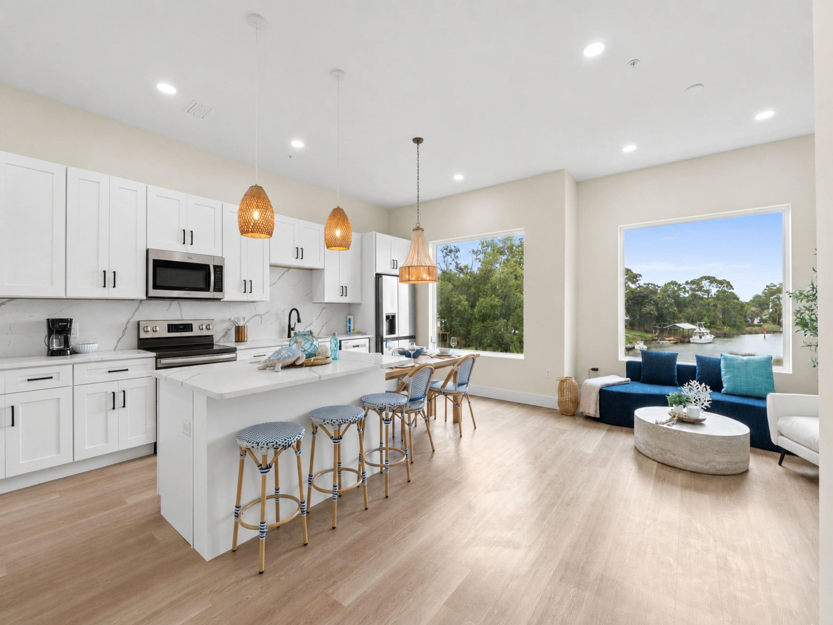 A modern kitchen with white cabinets, stainless steel appliances, and a central island with bar stools.