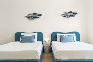 A double room with two beds, each with a blue headboard and white bedding. - 3002 Blue Lagoon B | Steps to Beach, Lagoon Views + Community Pool (Panama City Beach)