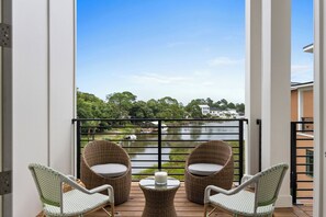 A balcony with wicker furniture and a view of a lake. - 3002 Blue Lagoon B | Steps to Beach, Lagoon Views + Community Pool (Panama City Beach)