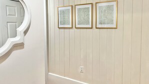 A hallway with a white door and three framed artworks on a wall. - 3-bedroom house in charming Old Town Bay St. Louis (Bay St. Louis)