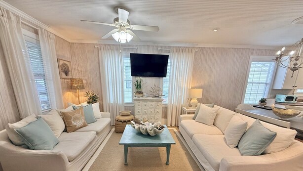 A living room with two white sofas, a coffee table, a television, and a ceiling fan. - 3-bedroom house in charming Old Town Bay St. Louis (Bay St. Louis)