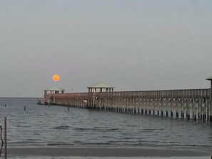 Une jetée s’avançant dans une eau calme, avec un coucher de soleil en arrière-plan.