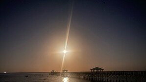 A beach at sunset with a pier extending into the water. - 3-bedroom house in charming Old Town Bay St. Louis (Bay St. Louis)