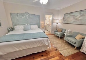 A bedroom with a large bed, a nightstand, a chair, a lamp, and a painting on the wall. - 3-bedroom house in charming Old Town Bay St. Louis (Bay St. Louis)