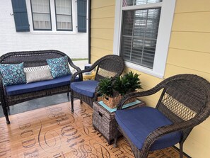 A patio area with wicker furniture, including a sofa and two chairs, a small table, and a potted plant. - 3-bedroom house in charming Old Town Bay St. Louis (Bay St. Louis)