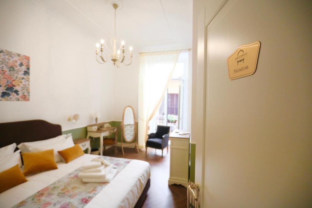 A hotel room with a bed, a desk, a chair, a mirror, and a sign indicating a premium room.