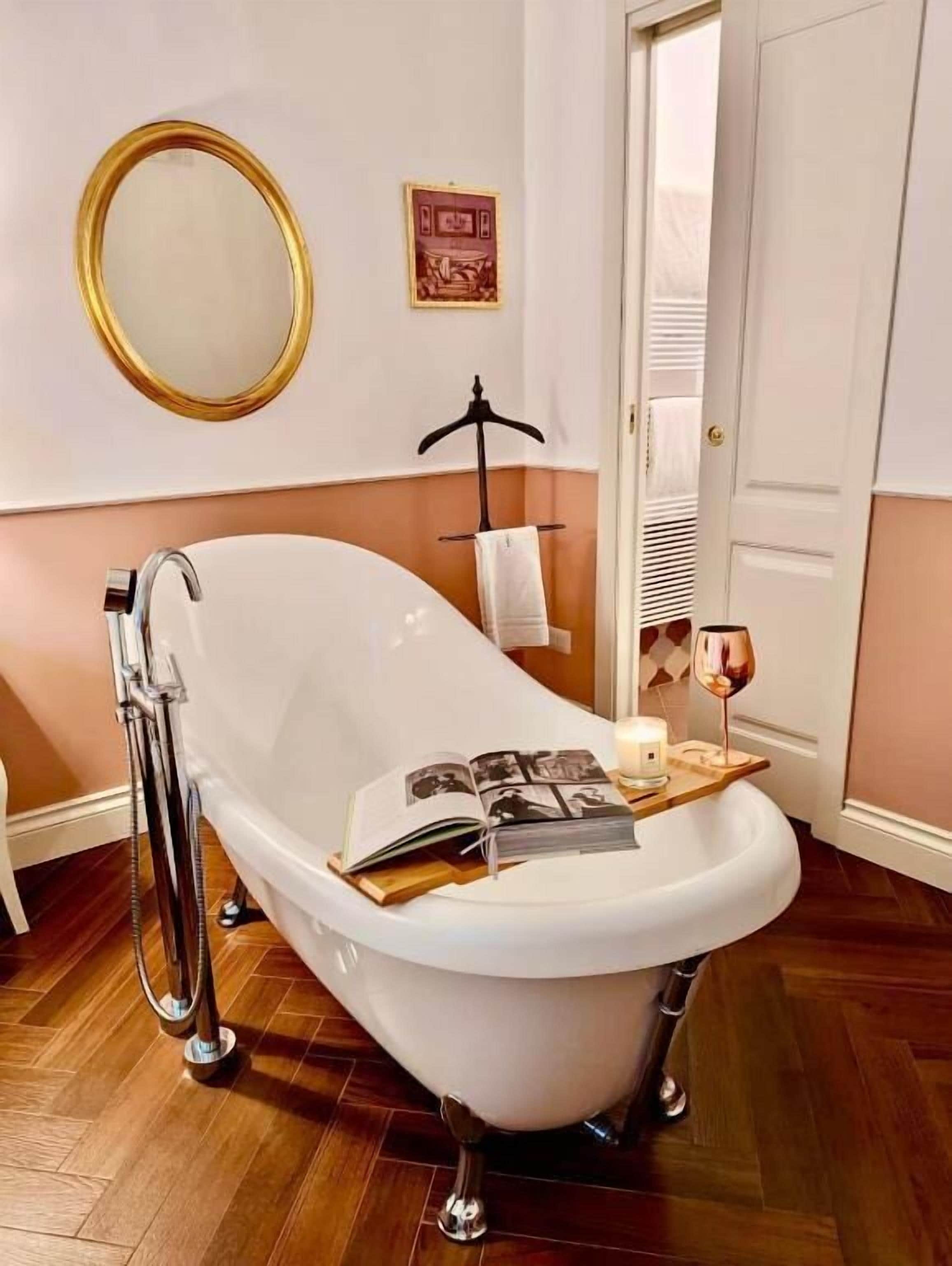 A bathroom with a freestanding bathtub, a mirror, and a towel rack.