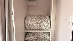 Habitació petita amb un llit, una petita prestatgeria i un penjador.