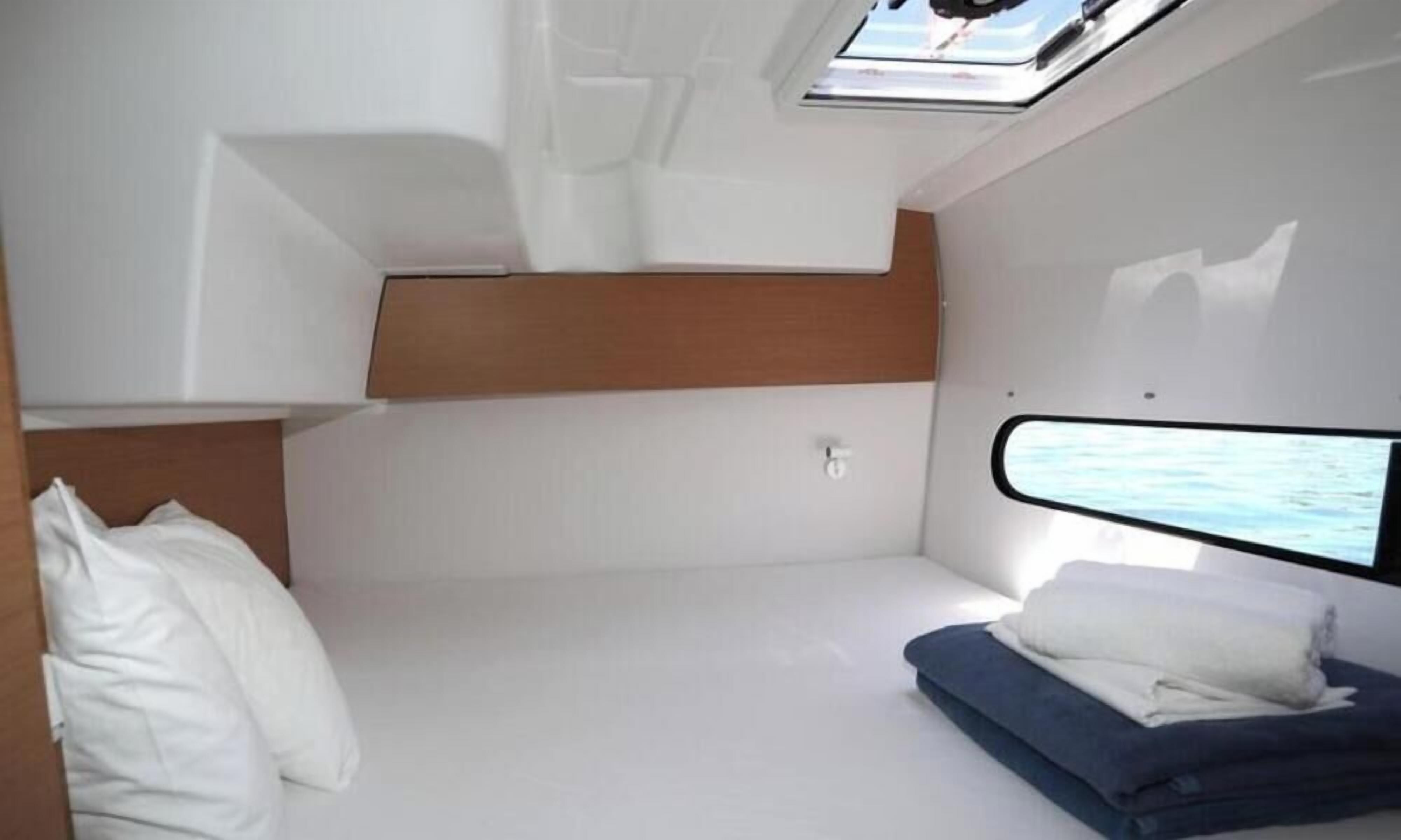 A compact, well-lit cabin with a bunk bed, a small window, and a neatly made bed.