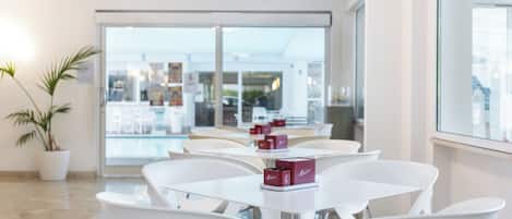 A modern interior with white furniture, a large glass door leading outside, and a potted plant.