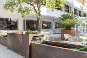 Un patio de hotel con mobiliario exterior, una fuente de agua y una palmera.