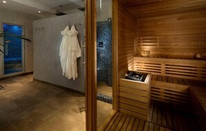 A modern spa room with a wooden sauna, a glass-enclosed shower area, and a tiled wall with a mosaic design. - Hotel Bassetti (Cervia)