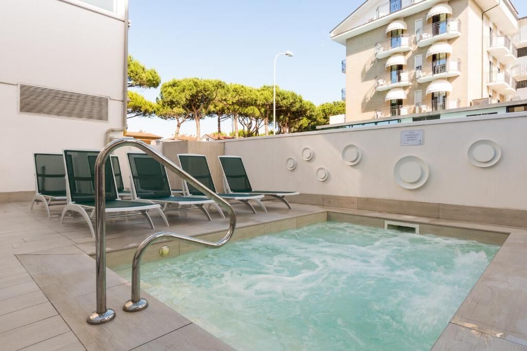 A pool area with lounge chairs and a jacuzzi.