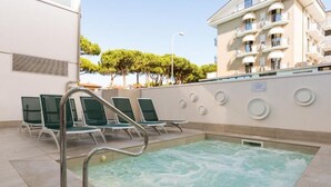 A pool area with lounge chairs and a jacuzzi. - Hotel Bassetti (Cervia)