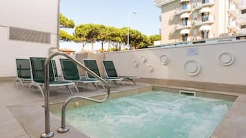 A pool area with lounge chairs and a jacuzzi.