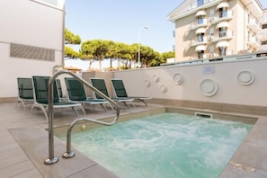 A pool area with lounge chairs and a jacuzzi.