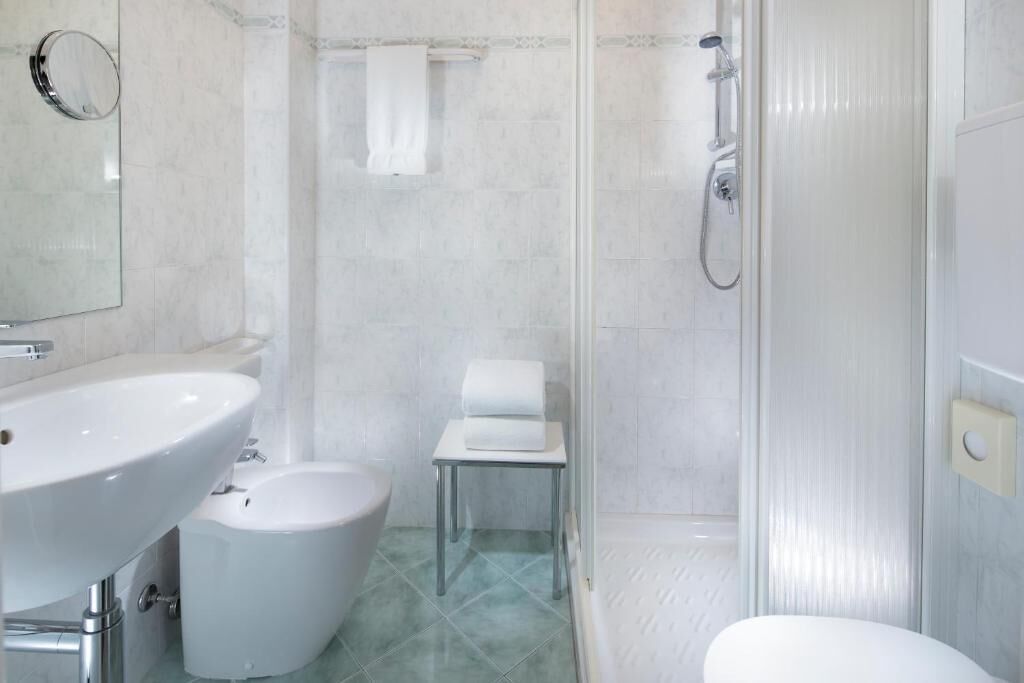 A bathroom with a sink, bidet, toilet, and shower.