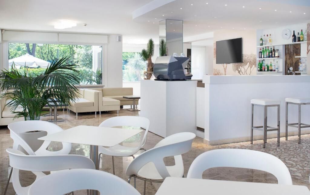 A modern bar area with a flat-screen TV, white bar stools, and a wine rack.