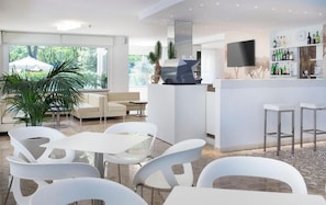 A modern bar area with a flat-screen TV, white bar stools, and a wine rack.