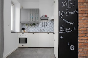 Una cocina moderna con armarios blancos, horno empotrado y pared de pizarra con escritura.