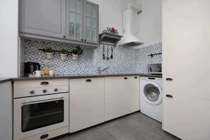 A modern kitchen with a built-in oven, a washing machine, and a tiled backsplash. - Cosy Apartment with a Desk | Close to the Underground | Smart TV (Warszawa)