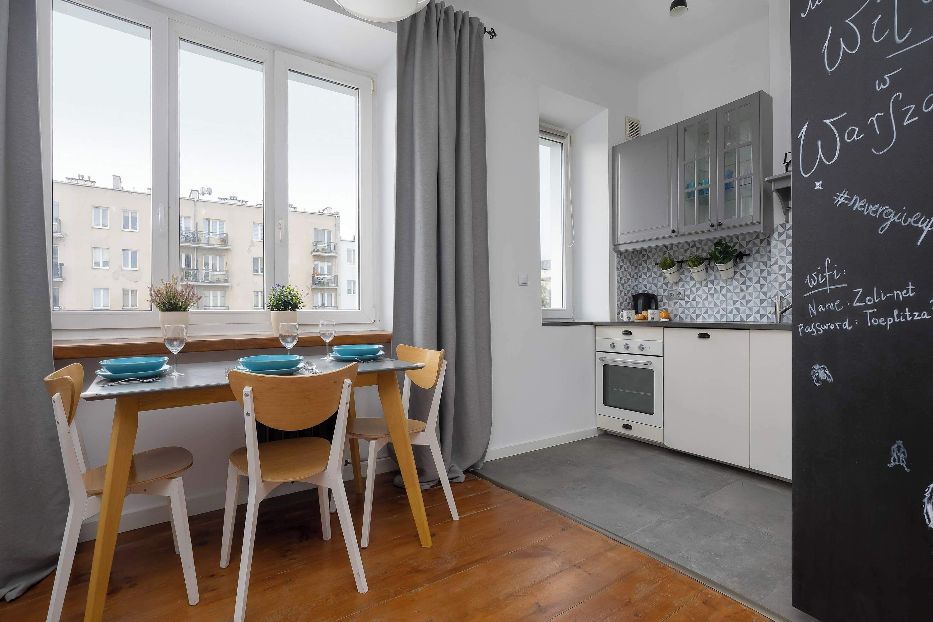 A modern kitchen with white cabinets, a stove, and a dining area with a table and chairs.