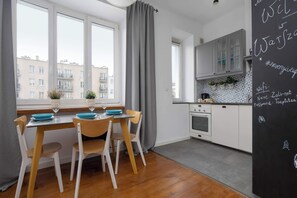 Une cuisine moderne avec des meubles blancs, une cuisinière et un coin repas comprenant une table et des chaises.