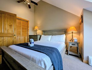 Ein Schlafzimmer mit einem großen Bett, zwei Nachttischlampen, einem Holzschrank und einem Deckenventilator.