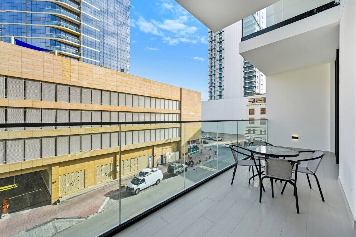A balcony with a glass railing overlooking a street with cars and buildings.