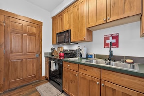A kitchen with wooden cabinets, a microwave, a stove, and a sink.