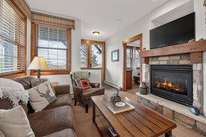 A living room with a fireplace, a sofa, a coffee table, and a television.
