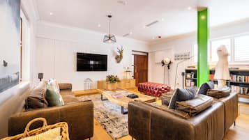 Uma sala de estar moderna com sofás de couro, uma televisão de tela plana, uma mesa de centro de madeira e uma estante de livros.
